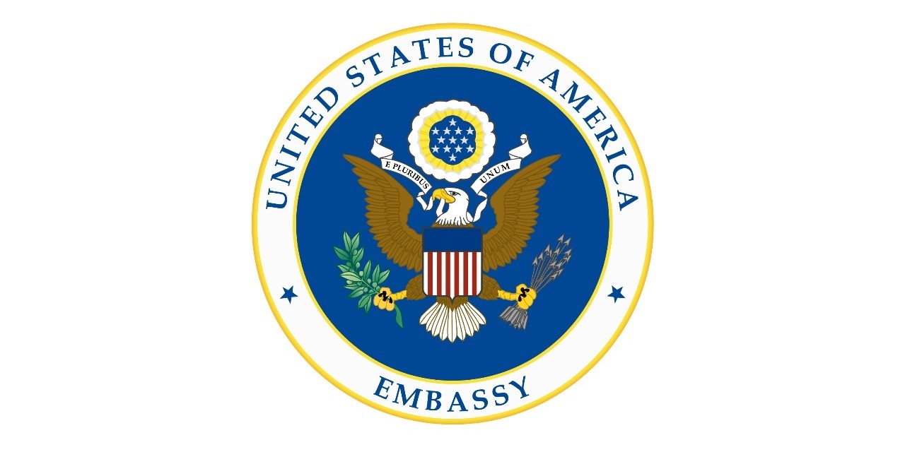 Logo of the United States of America Embassy, featuring the national emblem and official colors representing diplomacy.