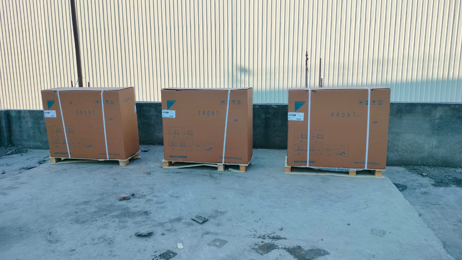 Three boxes on pallets positioned in front of a building, showcasing a clear view of the structure behind them.