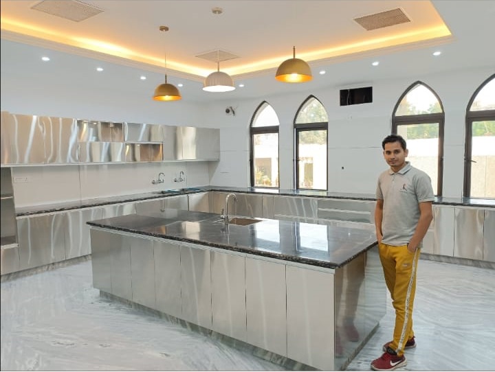 A man stands in a modern kitchen featuring sleek stainless steel appliances, showcasing a contemporary culinary space.