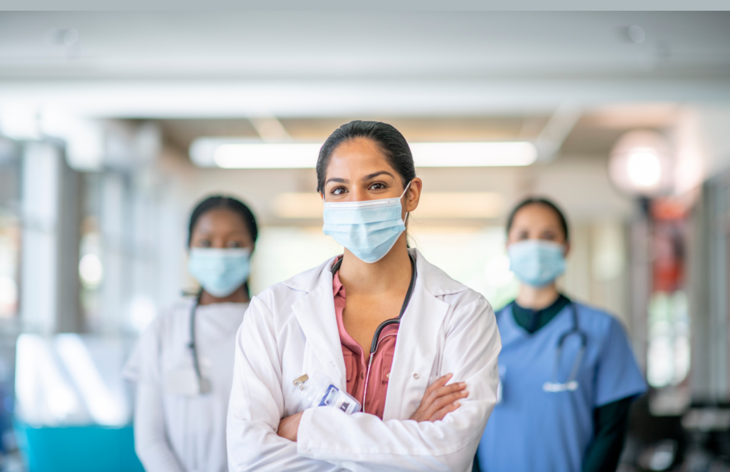 A diverse group of healthcare professionals stands confidently in a hospital corridor, showcasing teamwork and dedication.