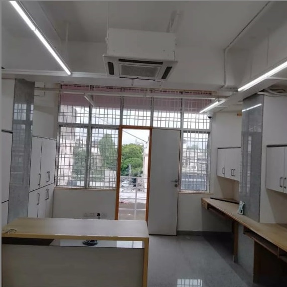 Bright, modern room features white cabinets, a wooden table, an open door, and large windows with greenery visible outside.