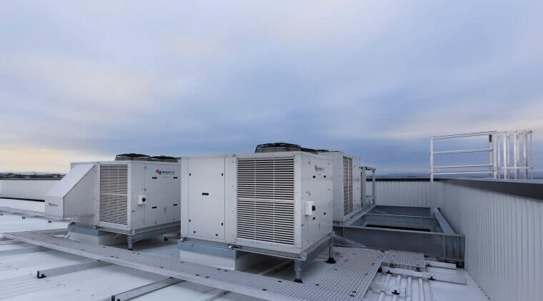 Rooftop view of industrial air conditioning units against a cloudy sky, showcasing modern HVAC equipment on a building.